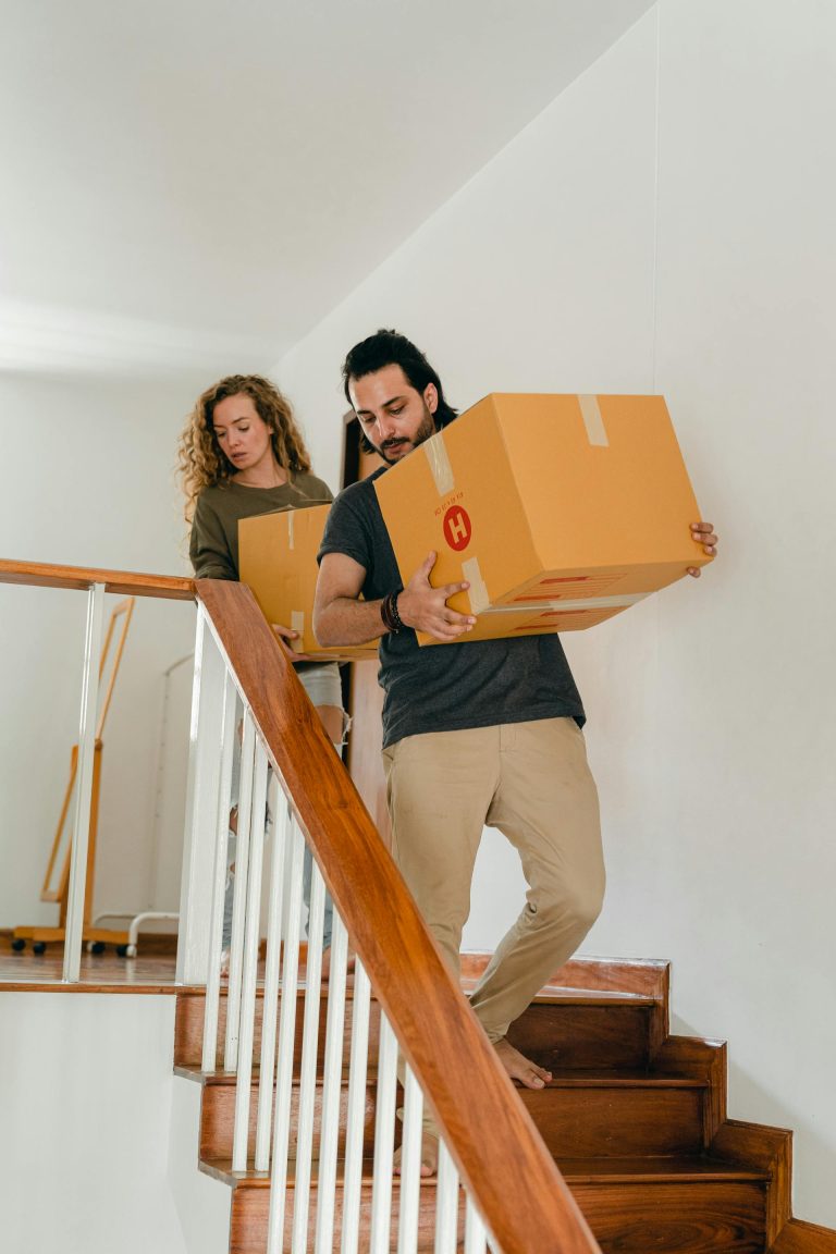 Two person moving and carrying big boxes on the stairs.